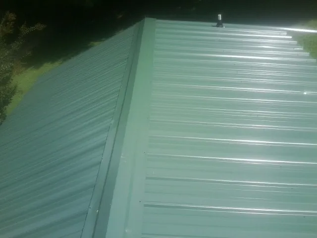 New green metal panels meeting at the ridge of a roof — Flat Roof Repair work by our crew in Steen