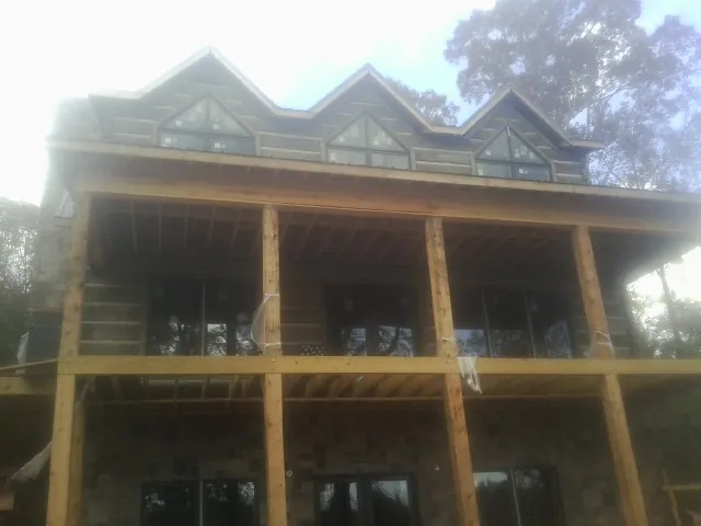 Dormers and porch framing on a large log home under construction — Roof Coating work by our crew in Steen