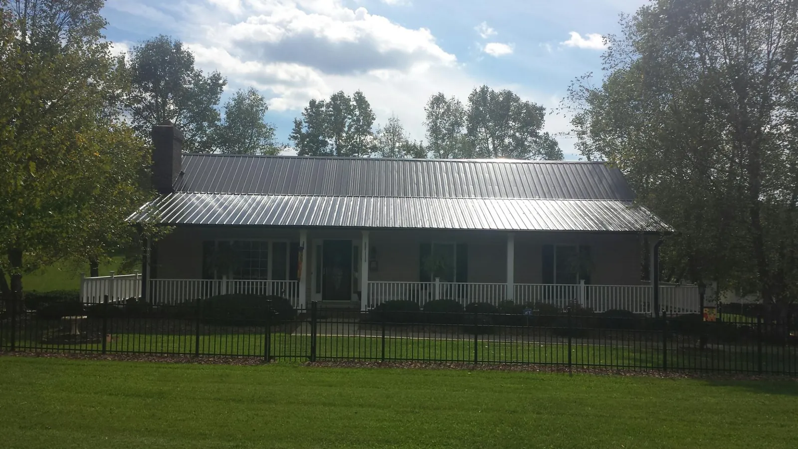 Gray metal roof on a brick ranch with a full width front porch — Gutter Guard Installation work by our crew in Steen