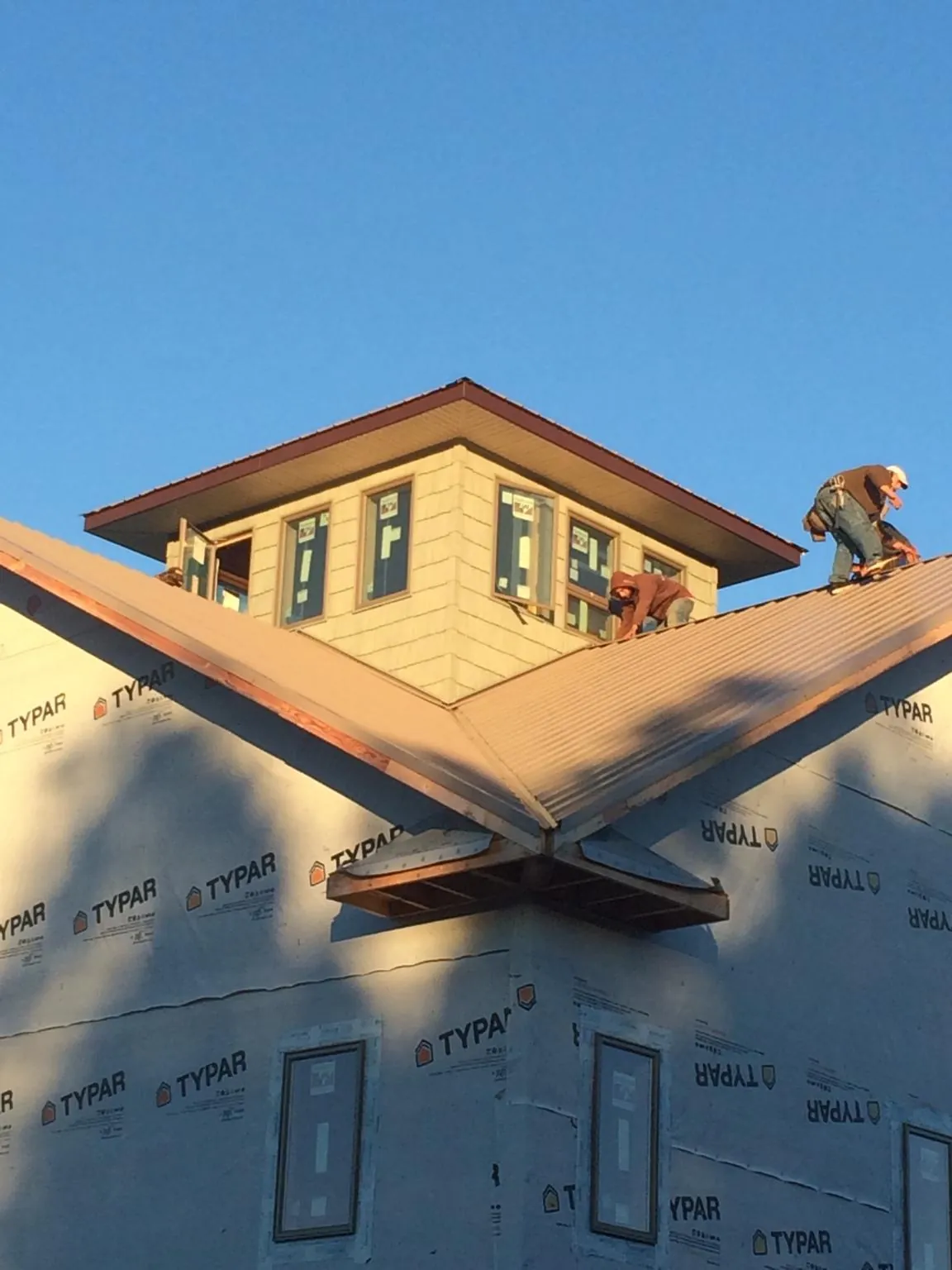 Roofers working around a rooftop cupola on a new metal roof at sunset — Roof Waterproofing in Steen by Roofing Brothers